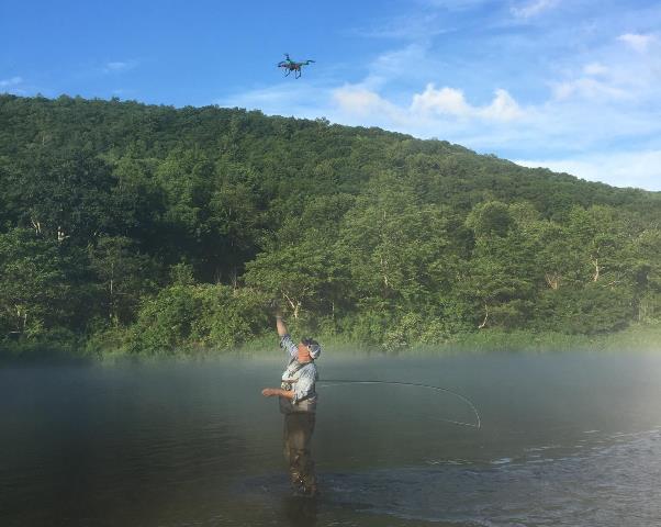 Dave getting a drone beer delivery on the West Branch after landing a fish.  Photo by Beth Zmijewski